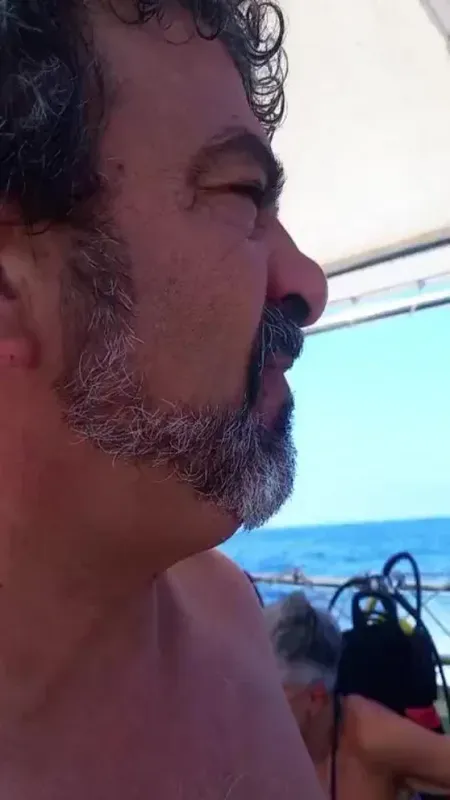 Portrait rapproché d'un homme barbu les yeux fermés sur un bateau