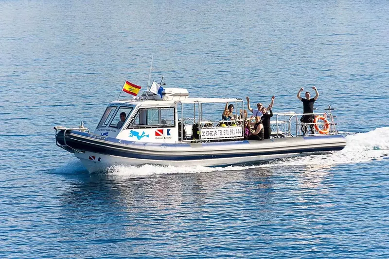 Bateau de plongée en mer avec des passagers souriants et levant les bras