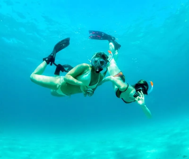 Deux plongeuses s'amusent sous l'eau dans une eau turquoise claire