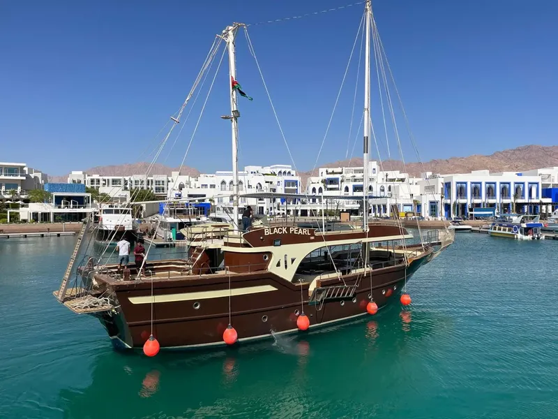 Bateau de plongée amarré dans un port ensoleillé avec des personnes