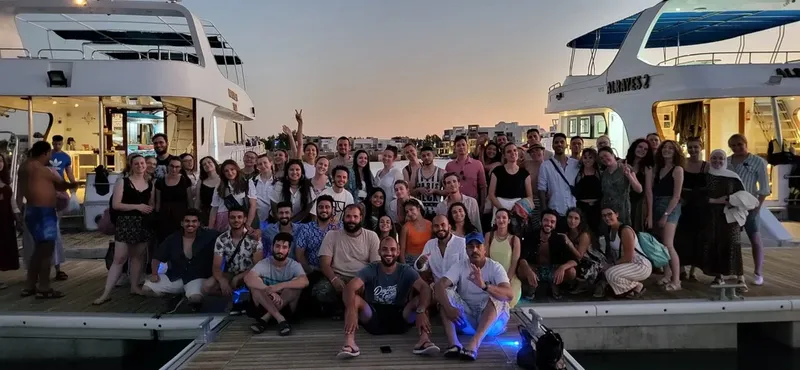 Groupe de personnes souriantes posant sur un ponton devant des bateaux