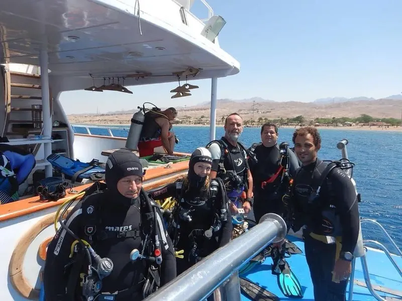Groupe de plongeurs souriants sur le pont d'un bateau en mer