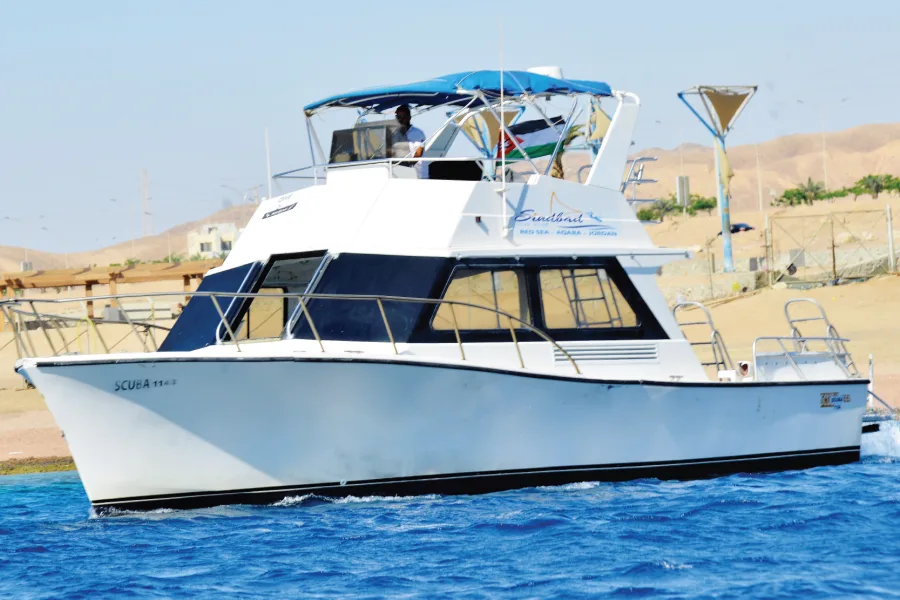 Bateau de plongée blanc et bleu navigue sur une mer turquoise
