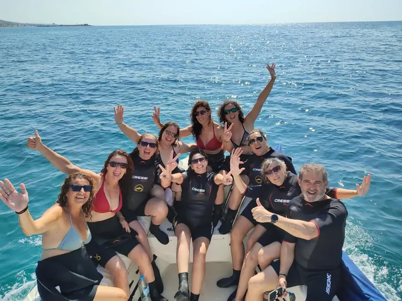 Groupe de plongeurs souriants et enthousiastes sur un bateau en mer