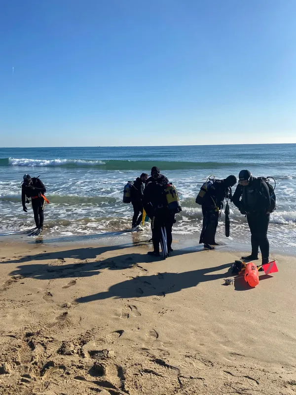 Plongée : groupe de personnes équipées sur une plage ensoleillée