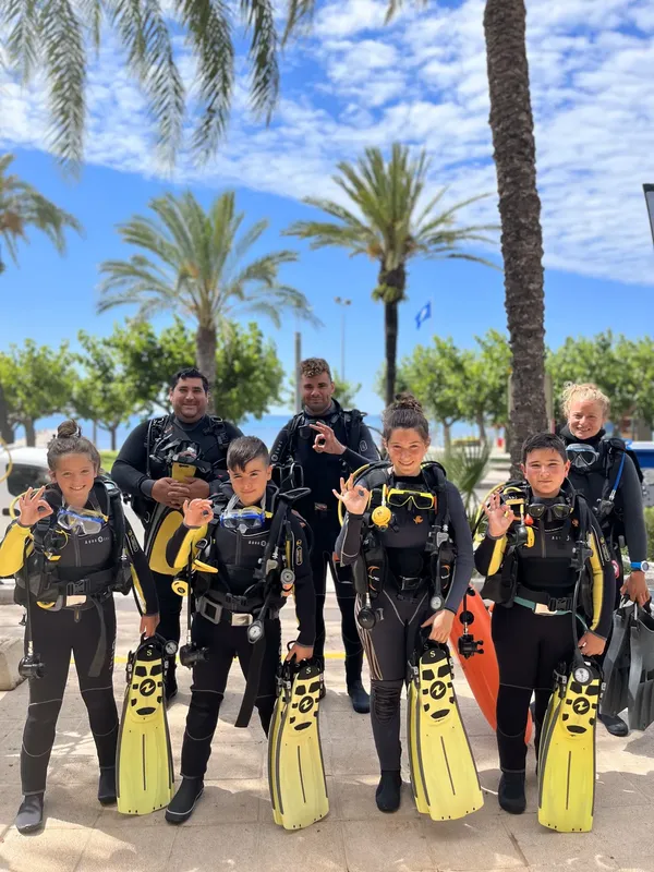 Groupe de plongeurs souriants équipés prêts pour une sortie en mer