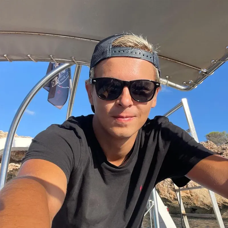 Jeune homme souriant portant des lunettes de soleil sur un bateau