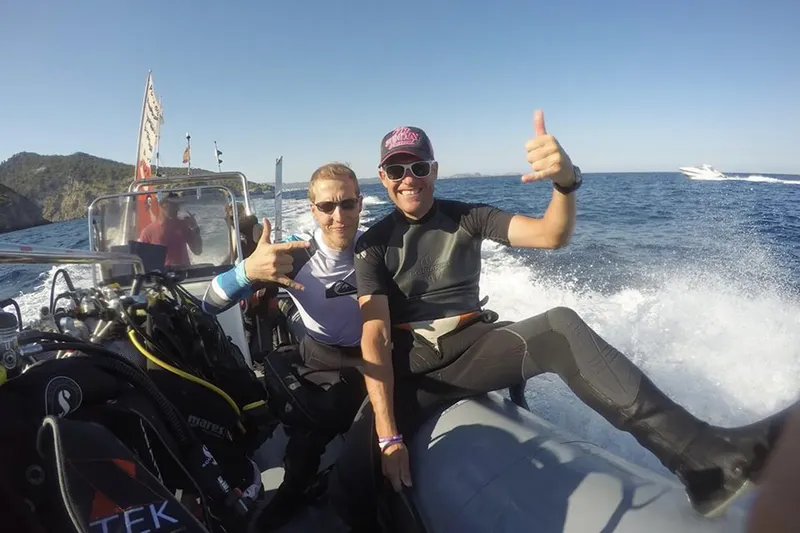 Deux plongeurs souriants font un signe de pouce levé sur un bateau