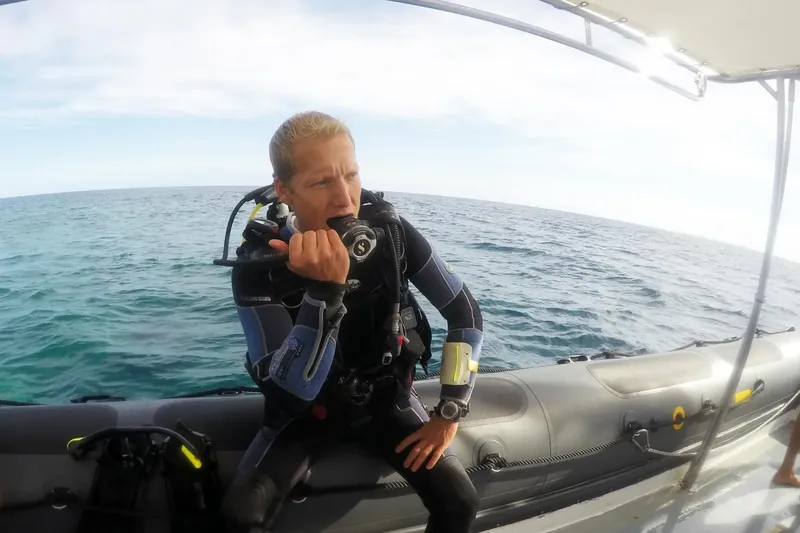 Plongeur assis sur un bateau pneumatique, vérifiant son équipement