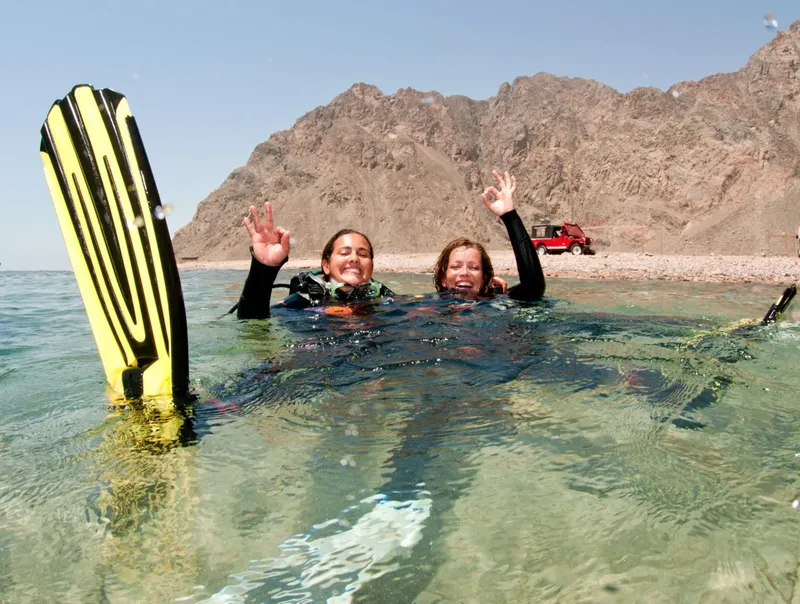 Deux plongeuses souriantes font signe avec les mains dans l'eau