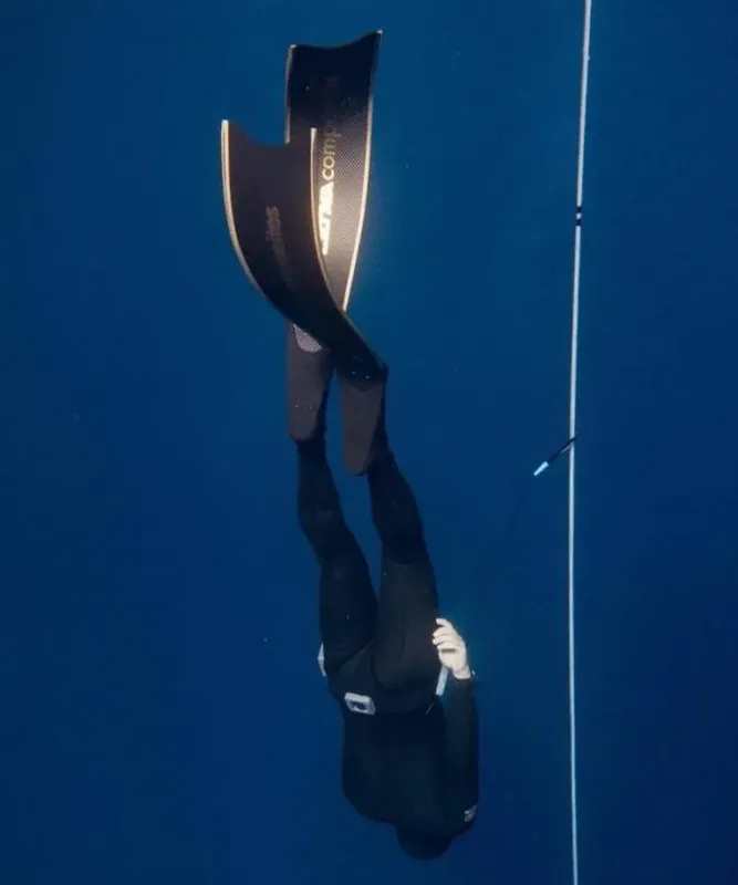 Apnéiste descendant le long d'un câble dans l'eau bleue