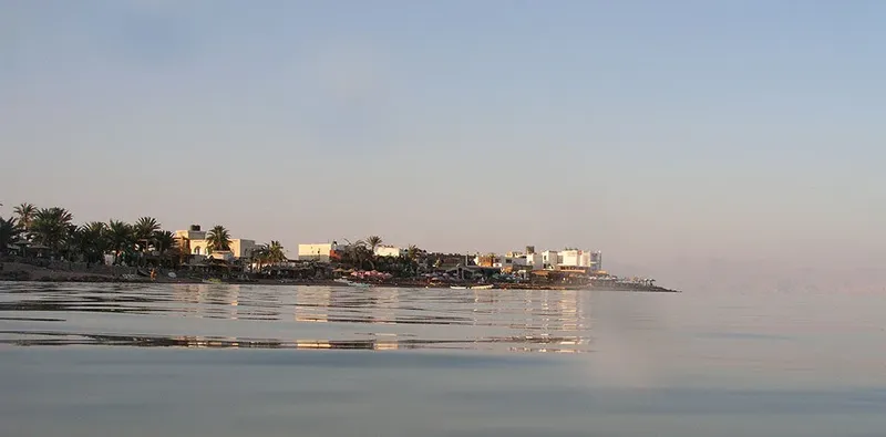Vue d'une côte avec bâtiments, bateaux et mer calme au lever du soleil