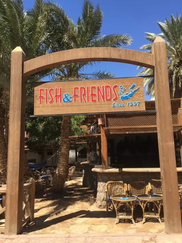Entree d'un centre avec une enseigne en bois et des tables vides