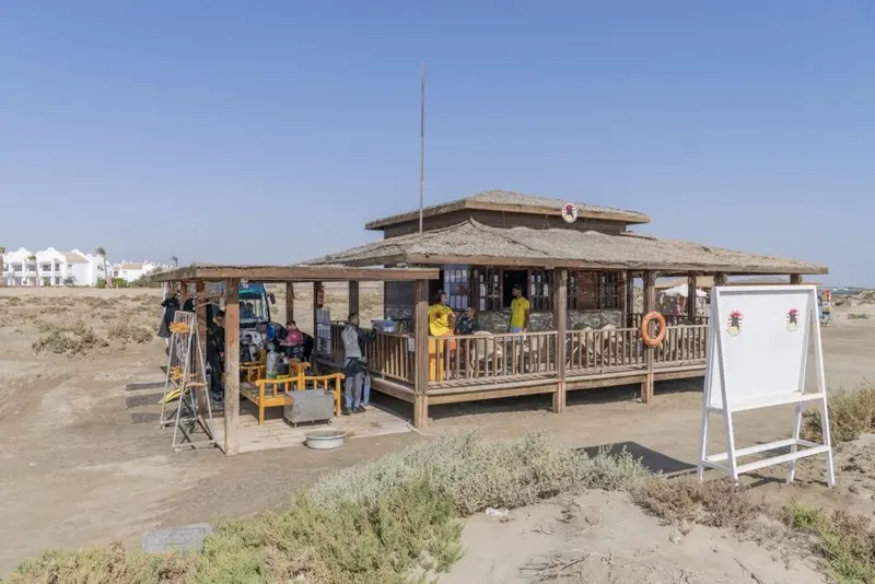 Bâtiment bas sur plage avec équipement de plongée et personnes