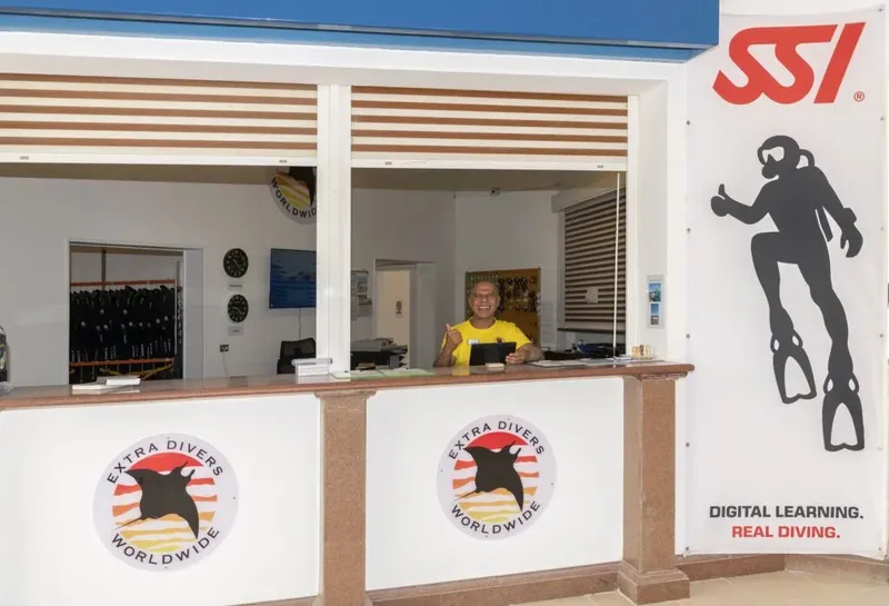 Comptoir d'accueil d'un centre de plongée avec un employé souriant