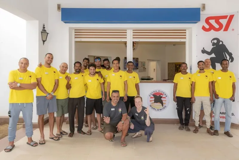 Equipe souriante devant le comptoir d'accueil d'un centre de plongée