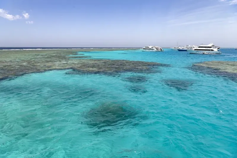 Vue aérienne d'une mer turquoise avec des bateaux et un récif corallien