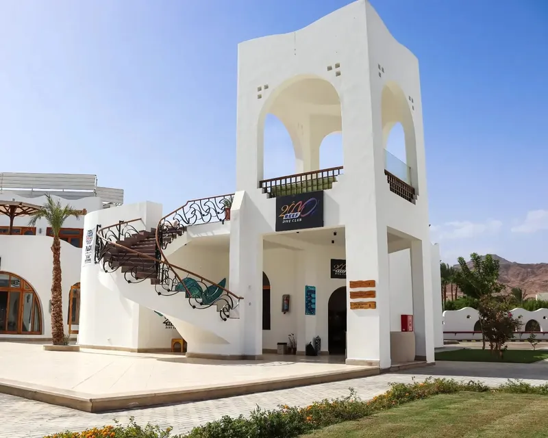 Architecture blanche d'un centre de plongée avec logo et végétation tropicale