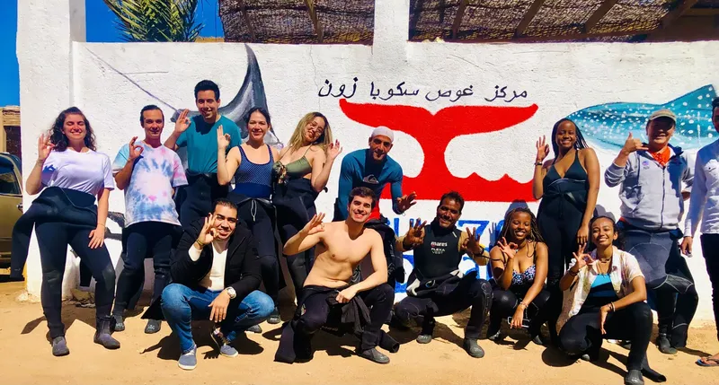Groupe de personnes souriantes devant un mur peint avec un requin baleine