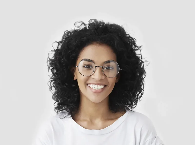 Portrait d'une jeune femme souriante avec des cheveux bouclés et des lunettes