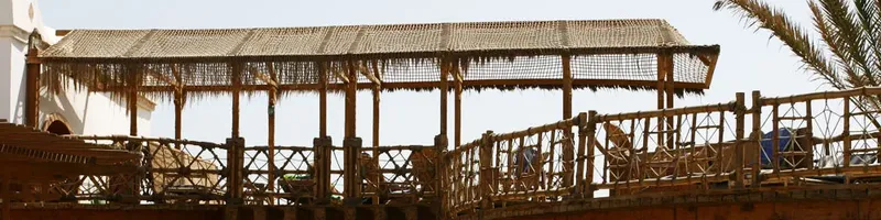 Structure en bois et roseaux abritant un espace détente au bord de l'eau