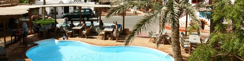 Vue d'une cour avec piscine, tables, chaises et quelques personnes