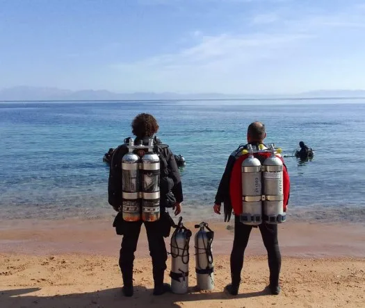 Deux plongeurs équipés regardent la mer avec d'autres en arrière-plan