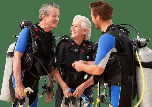 Trois plongeurs souriants équipés prêts pour une immersion en mer