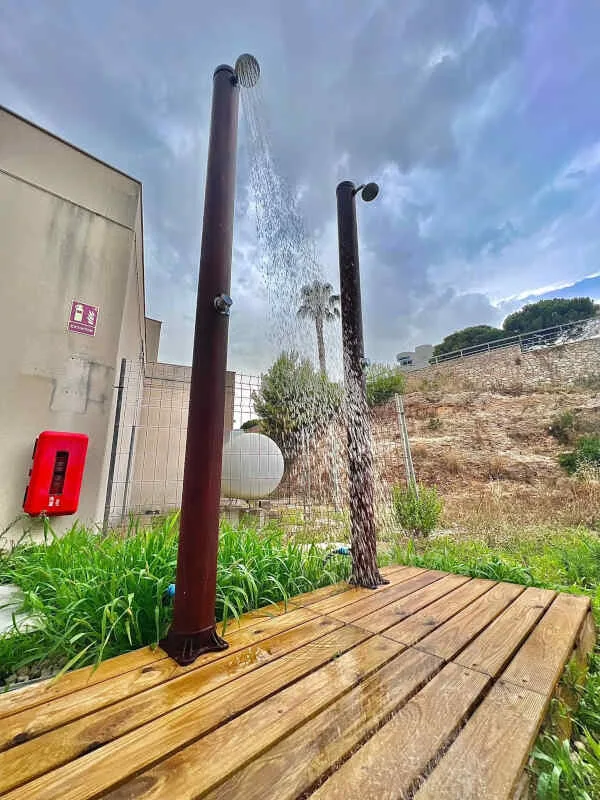 Deux douches extérieures en bois avec eau qui coule sur terrasse