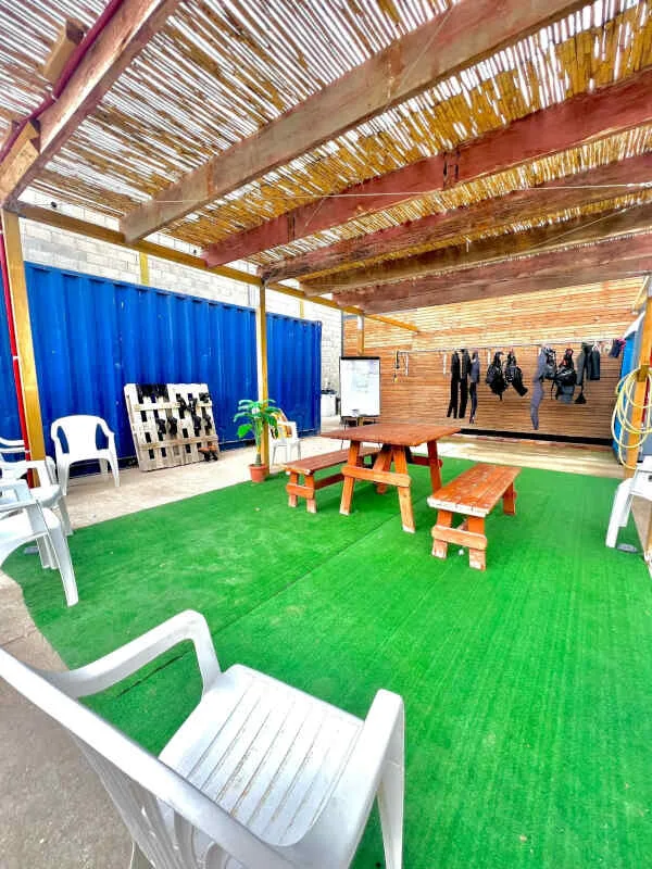 Espace détente extérieur avec tables, chaises, et matériel de plongée
