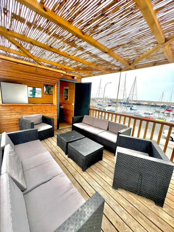 Terrasse aménagée avec salon de jardin, vue sur un port de plaisance