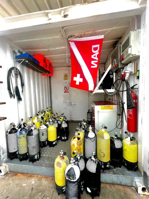Interieur d'un local de plongée avec des bouteilles et un drapeau Alpha