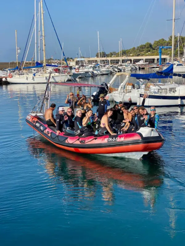 Groupe de plongeurs souriants à bord d'un bateau semi-rigide rouge