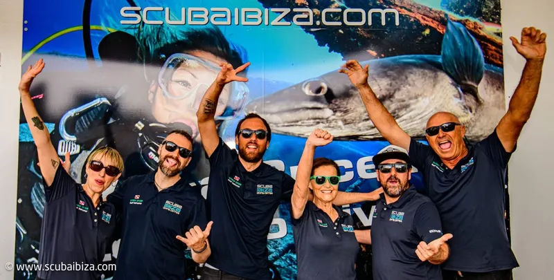Equipe souriante devant une grande image sous-marine, ambiance joyeuse