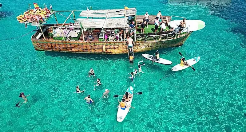 Bateau en bois avec des personnes nageant et faisant du kayak