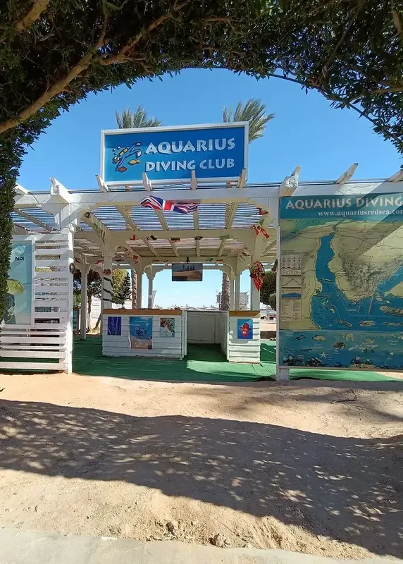 Entrée d'un club de plongée avec enseigne, cartes et parasols