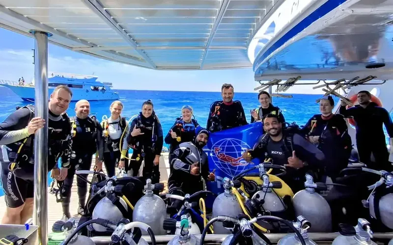 Groupe de plongeurs souriants sur un bateau avec des bouteilles
