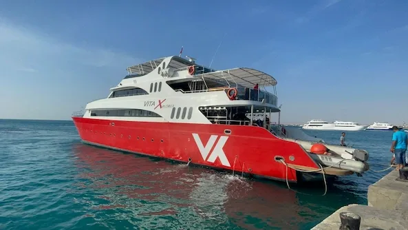 Grand bateau de plongée rouge et blanc amarré au port avec des personnes