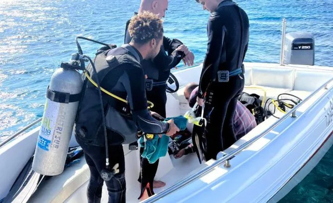 Plongeurs s'équipent sur un bateau pneumatique en préparation d'une sortie