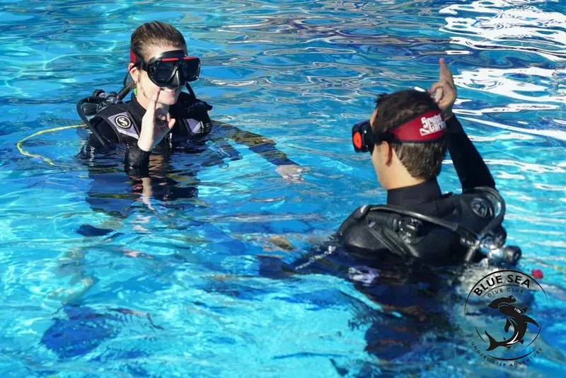 Deux plongeurs en formation communiquent sous l'eau dans une piscine