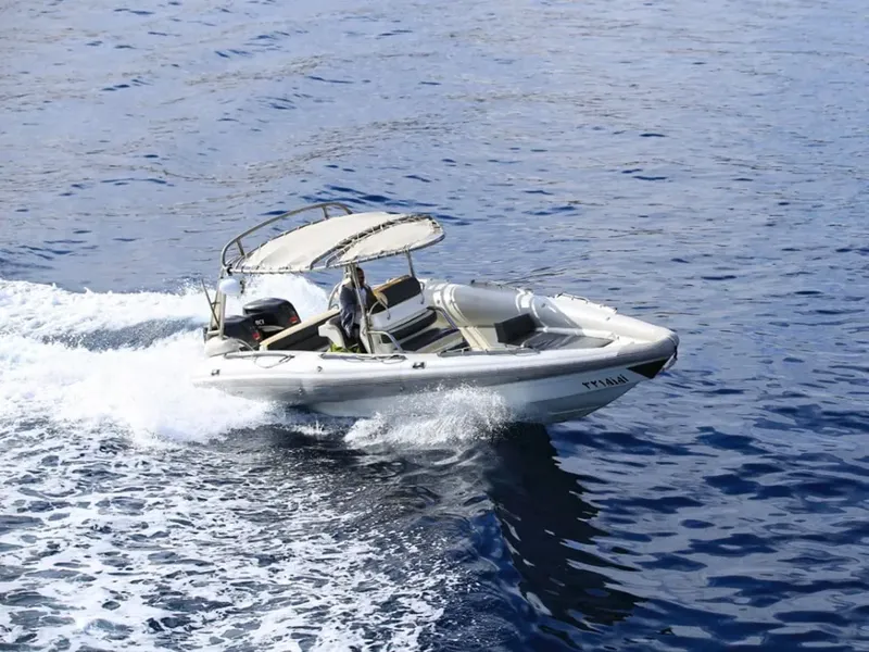 Un semi-rigide blanc navigue sur une mer bleue avec un passager