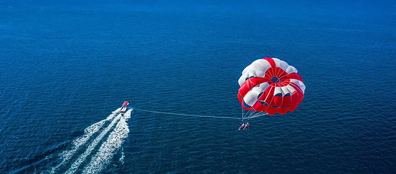 Personnes en parachute ascensionnel tirées par un bateau à moteur en mer