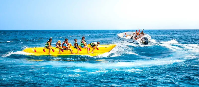 Personnes s'amusant sur une bouée banane tractée par un bateau rapide