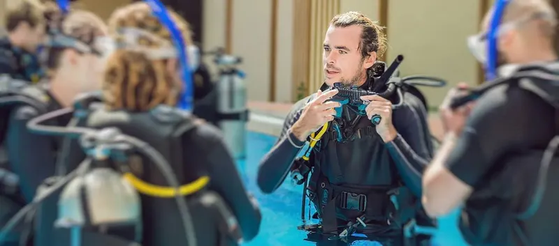 Instructeur de plongée explique l'équipement à des élèves en piscine
