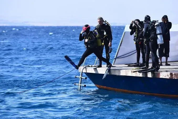 Plongeurs s'apprêtent à entrer dans l'eau depuis un bateau de plongée