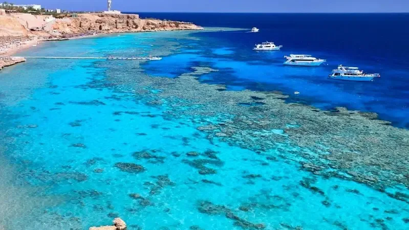 Vue aérienne d'une côte rocheuse avec des bateaux en mer turquoise