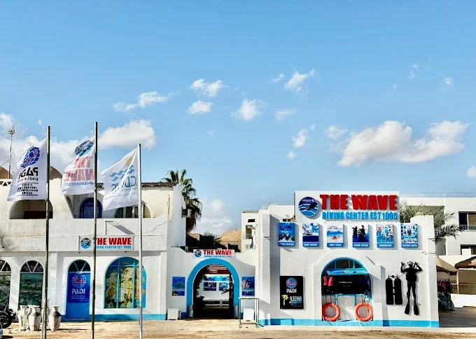 Façade d'un centre de plongée avec enseignes et drapeaux au soleil