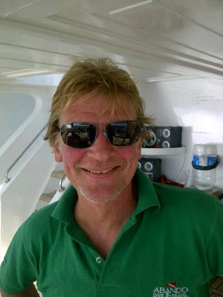 Homme souriant portant des lunettes de soleil sur un bateau de plongée
