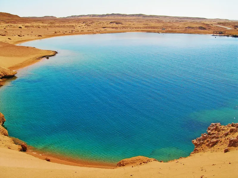 Vue aérienne d'une baie turquoise bordée de falaises désertiques