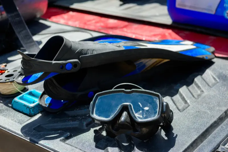 Palmes de plongée bleues et masque noir sur une surface sombre
